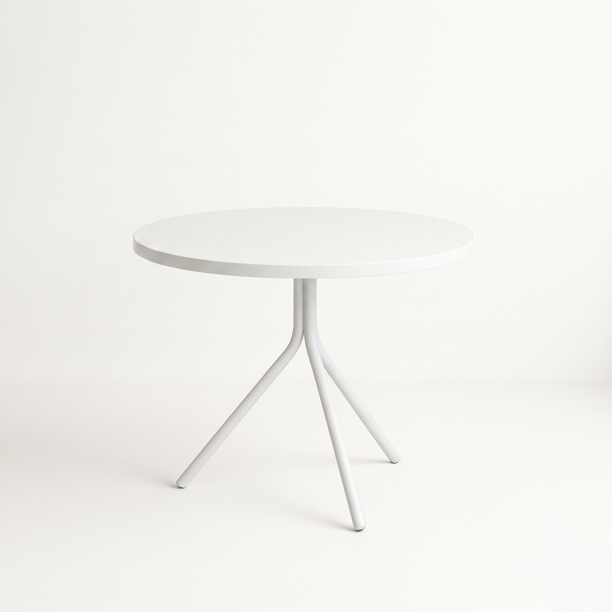 White round pedestal table with curved legs against a pale white background in a minimalist studio setting.